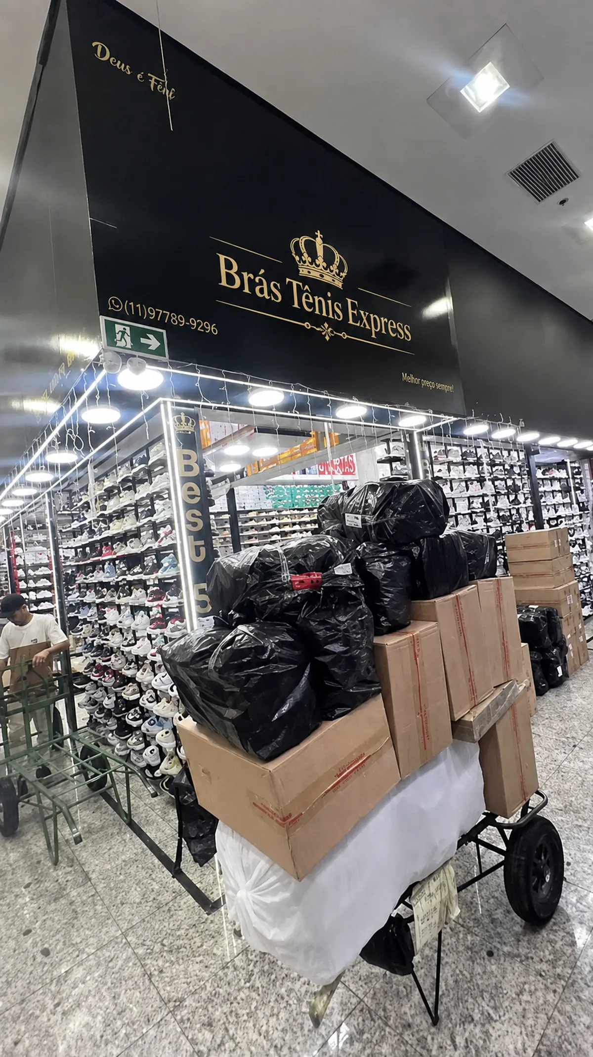 Fachada da loja Brás Tênis Express no Bom Retiro, São Paulo, com prateleiras cheias de tênis